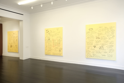 Three of the same sized paintings of text and doodles on yellow note paper are shown hanging side by side.