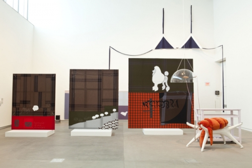 Installation view from von Bonin's 2011 show at the Kemper Art Museum. Features three fabric paintings increasing in size from left to right. all are primarily brown, red, and a deep green. they are mounted on small white platforms in the center of the gallery. to the right is a stuffed lobster over a three-pronged table stand. a large, navy fabric bikini top hangs on the wall in the background